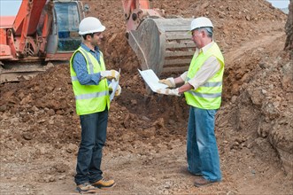 two engineers with plans in construction site