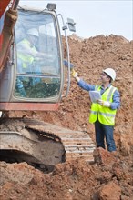 engineer handing plans to excavator driver