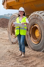 female engineer with plan next to dump truck