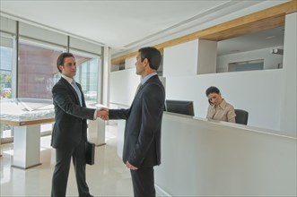 two businessmen shaking hands in office reception