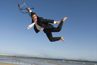 Businessman kite surfing on beach portrait