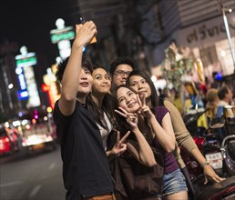 Friends taking pictures on city street at night