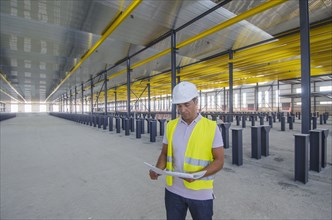 Hispanic worker reading blueprints in warehouse