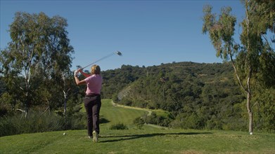 Caucasian woman teeing off on golf course