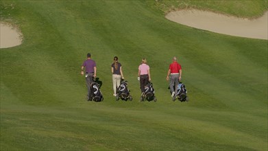 Caucasian friends pulling golf bags on course