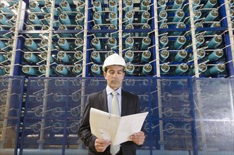 Hispanic businessman reading folder in power plant