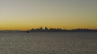 Silhouette of urban waterfront skyline at sunset
