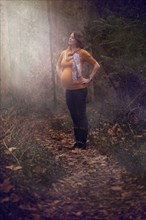 Pregnant Caucasian woman standing in forest