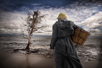 Caucasian woman carrying basket on windy beach