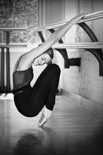 Caucasian ballet dancer stretching at barre in studio
