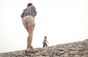 Caucasian mother and son walking on rocky hillside