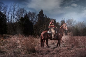 Caucasian woman riding horse in rural field