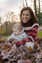 Mother and son sitting in autumn leaves