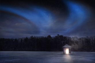 Glowing fishing cabin on remote frozen lake