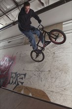 Man riding bicycle on wall indoors