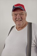 Caucasian man wearing baseball cap and suspenders