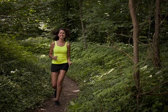 Hispanic woman running on path in forest