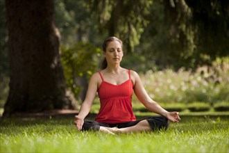 Caucasian woman doing yoga meditating in field