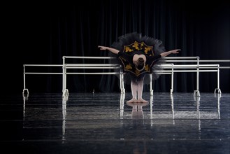 Caucasian ballerina bowing on dark stage
