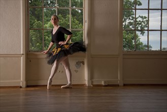 Caucasian ballerina posing at window in studio