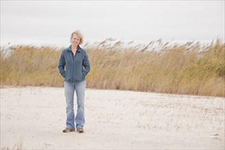 Caucasian woman standing on beach in wind