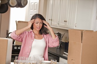 Frustrated Smiling Hispanic in kitchen with cardboard boxes