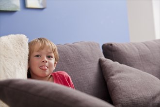 Caucasian boy with tongue out on sofa