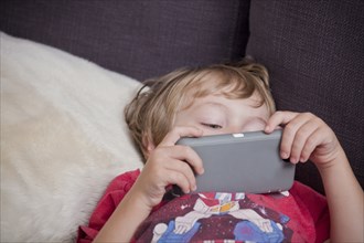 Caucasian boy laying on sofa watching cell phone