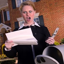 Angry woman reading mail at mailbox