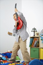 Mixed race boy playing toy guitar