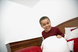 Mixed race boy playing on bed
