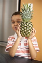 Mixed race boy holding pineapple