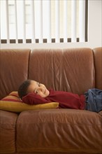 Mixed race boy laying on couch