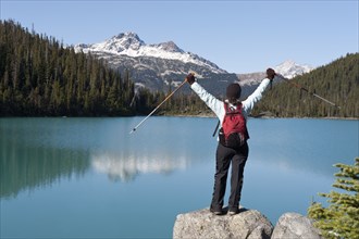 Hispanic hiker standing on rock near remote lake