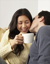 Husband kissing wife drinking coffee