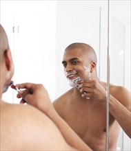 Man shaving in bathroom mirror
