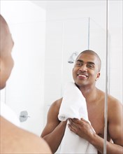 Man in bathroom wiping face with towel