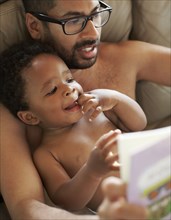 Father reading book to African American baby