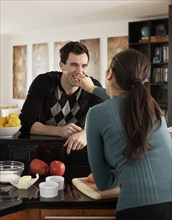 Woman feeding husband in kitchen