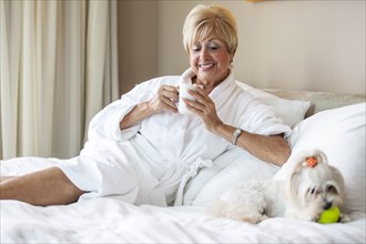 Older Caucasian woman and dog relaxing on bed