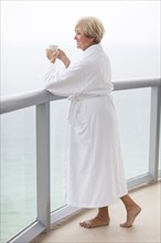 Older Caucasian woman drinking coffee on balcony