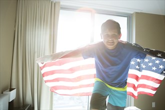 Hispanic boy using American flag as cape