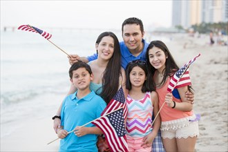 Hispanic family waving American flags on beach