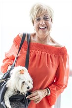Older Caucasian woman carrying dog in purse