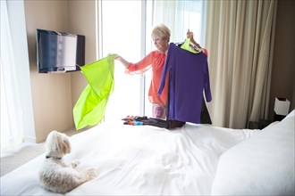 Older Caucasian woman choosing outfit in bedroom