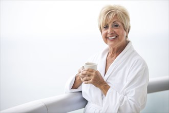 Older Caucasian woman drinking coffee on balcony