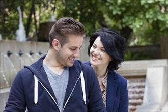 Caucasian couple smiling by urban fountain