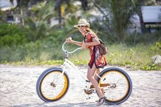 Hispanic woman riding bicycle on beach