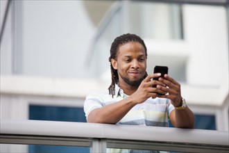 African American businessman using cell phone on balcony