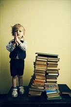 Boy standing near stacks of books